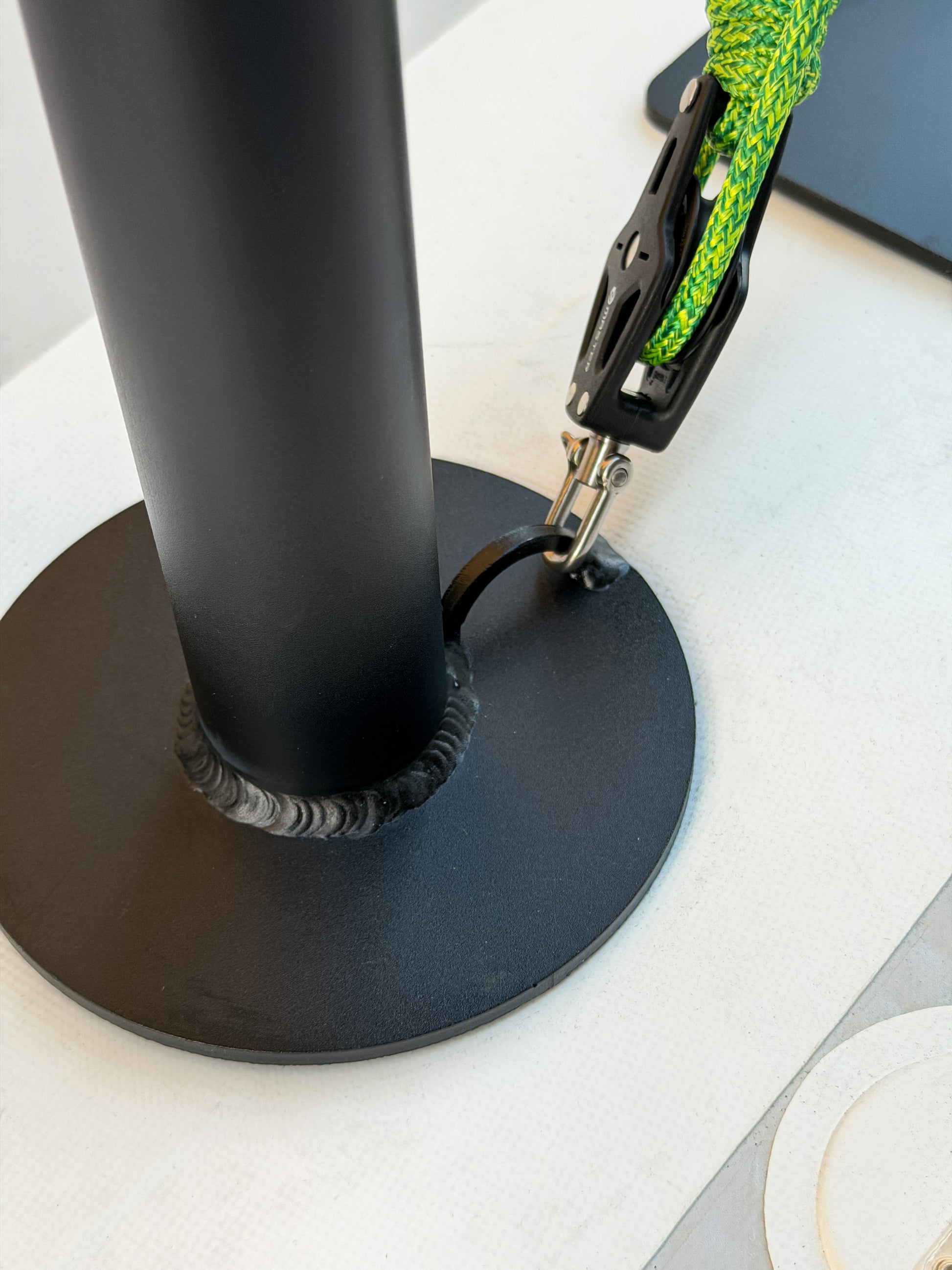 Black chair with a rope around its base on a white surface