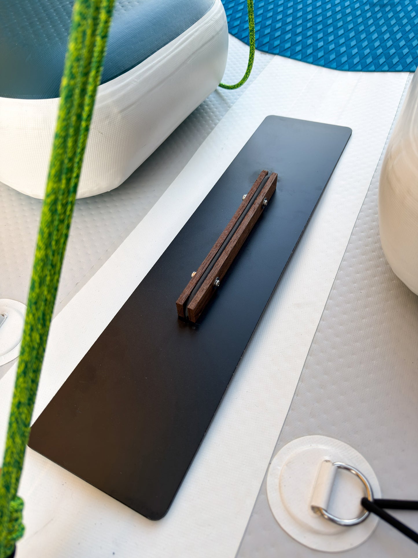 Black desk mat on a white surface with a pen and plant