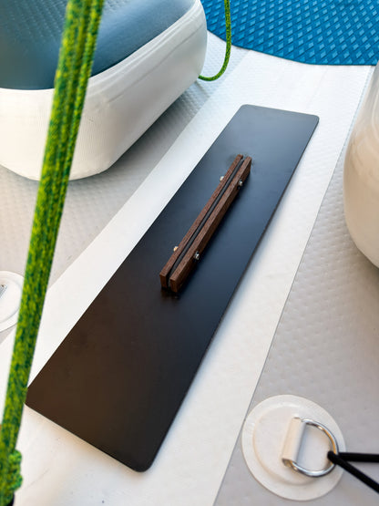 Black desk mat on a white surface with a pen and plant