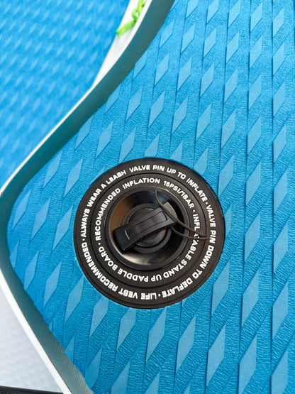 Close-up of a blue inflatable paddle board with valve pin and text