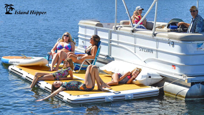 People lounging on an inflatable platform attached to a boat with 'Island Hopper' branding.