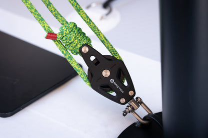 Close-up of a green rope with a black metal clip on a white surface
