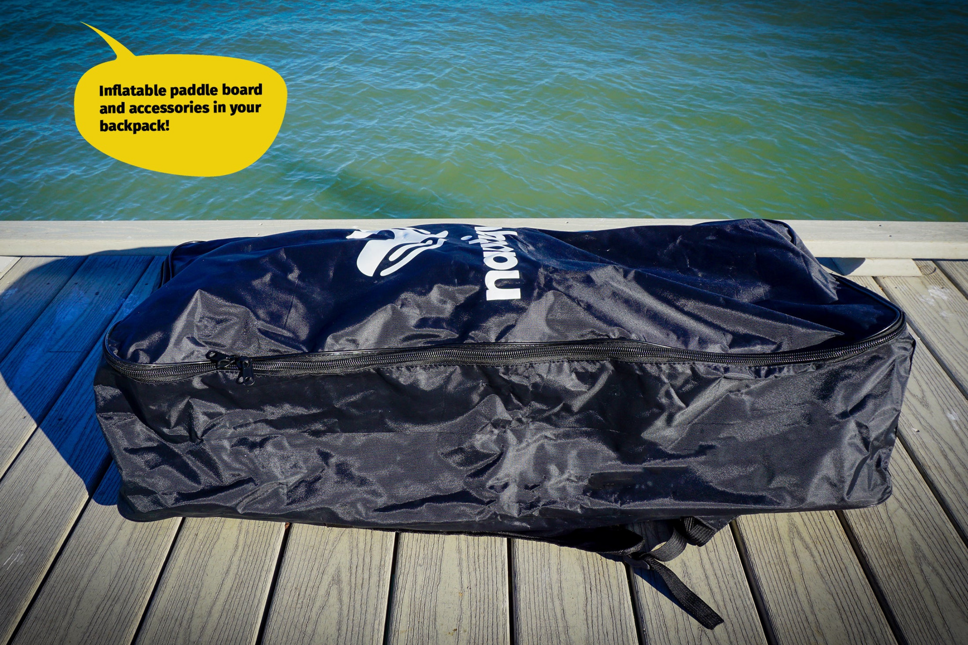 Blue inflatable paddle board bag with 'NRS' branding on a wooden dock by a body of water.