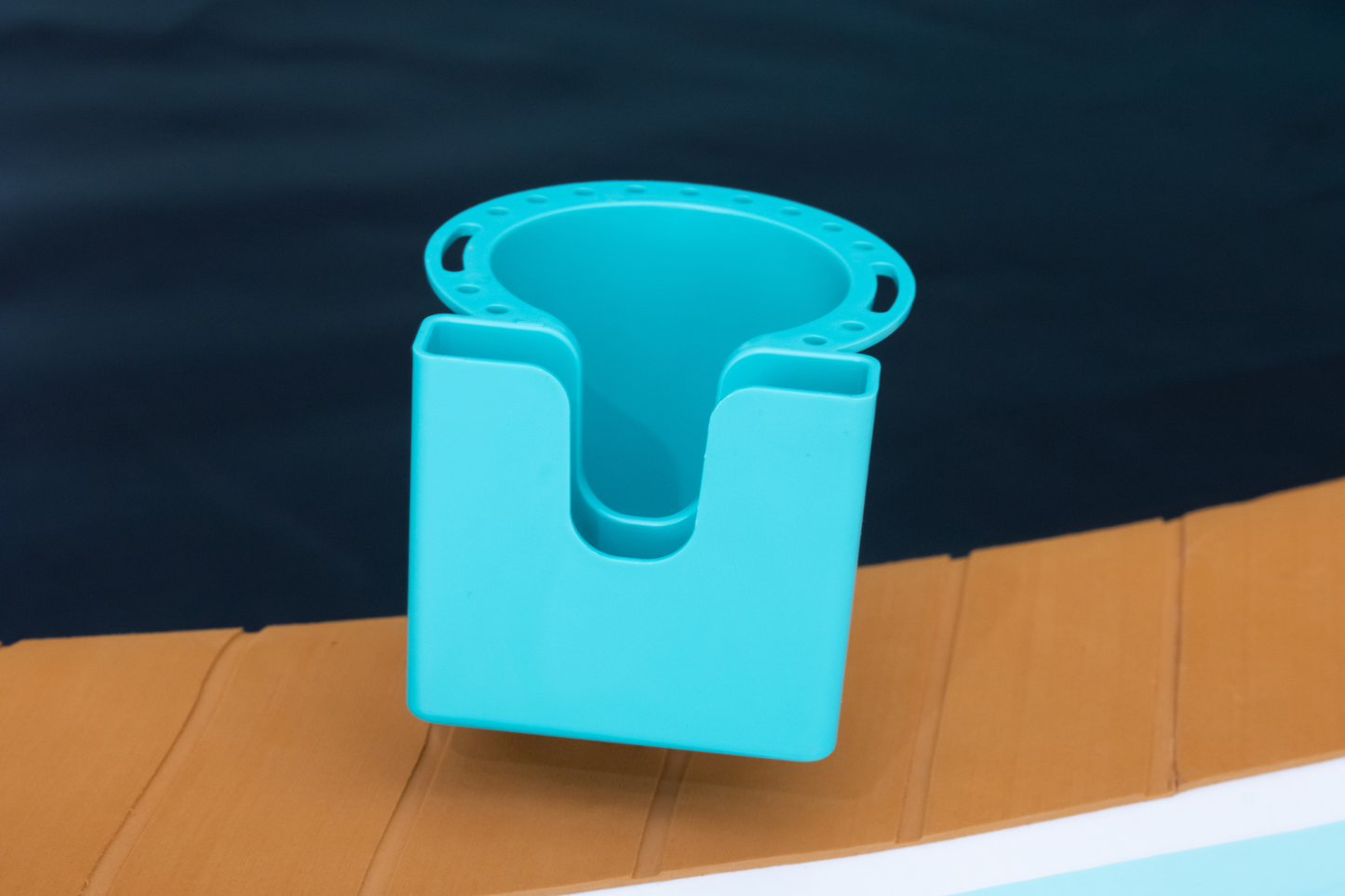 Turquoise cup holder on a wooden deck with water in the background