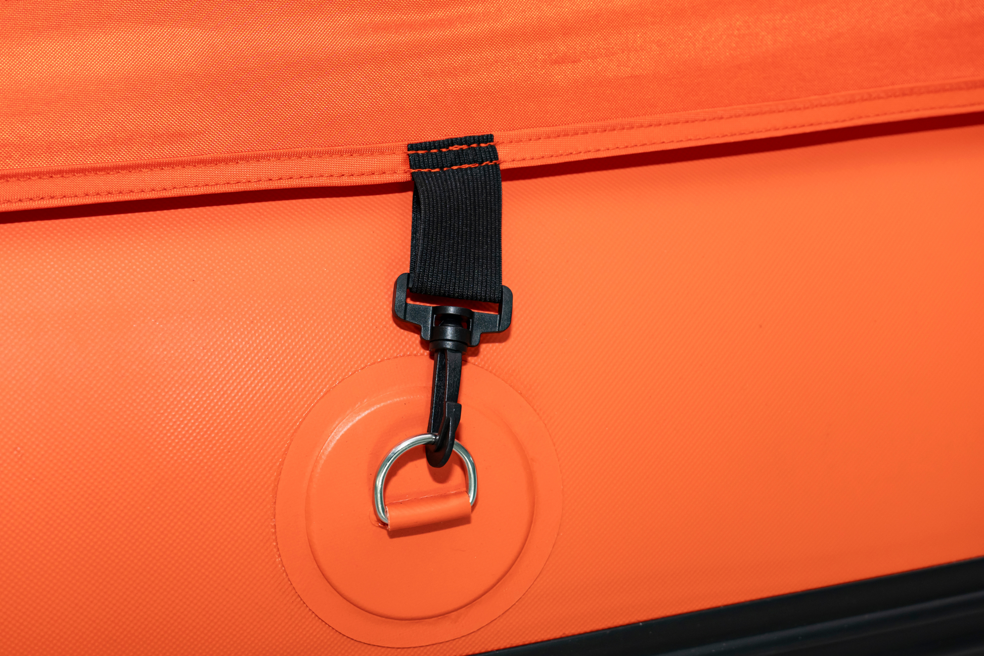Close-up of an orange bag with a black strap and metal ring detail.