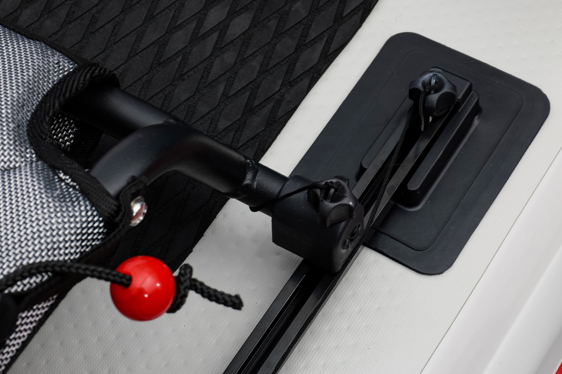 Close-up of a black carabiner with a red button on a textured surface.