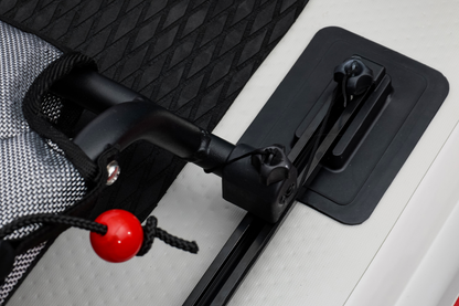 Close-up of a black carabiner with a red button on a textured surface.