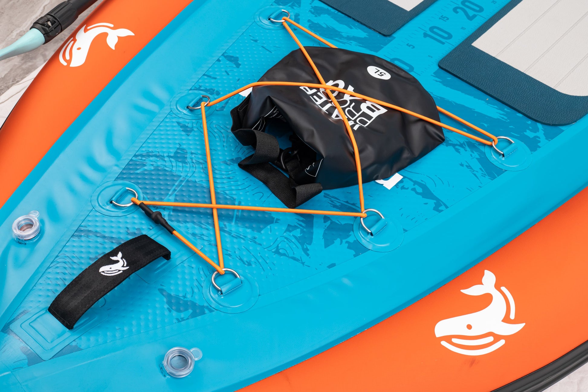 Close-up of an inflatable paddle board with a black bag and orange straps.