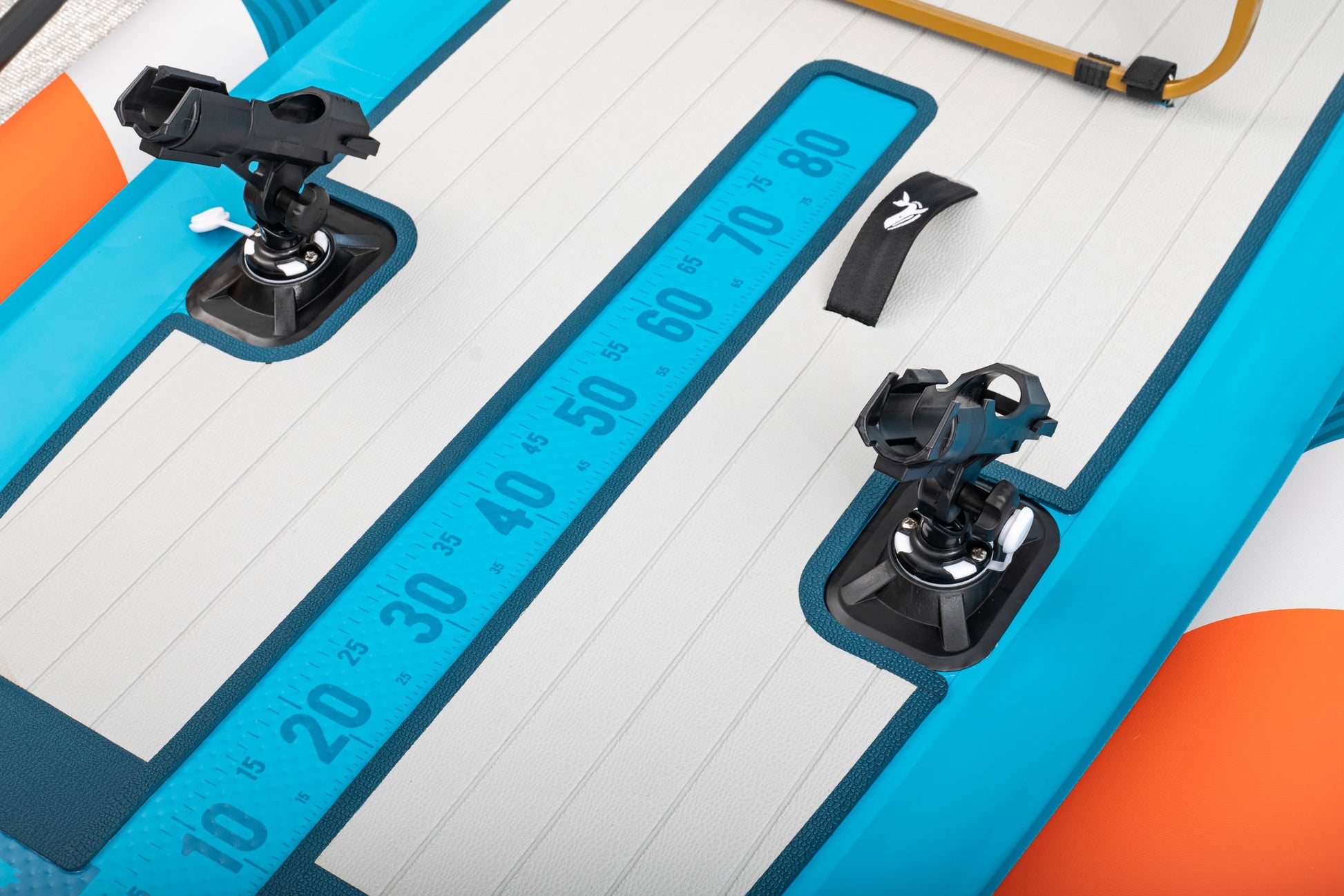 Close-up of a blue and orange inflatable paddle board with measurement scale and mounting brackets.