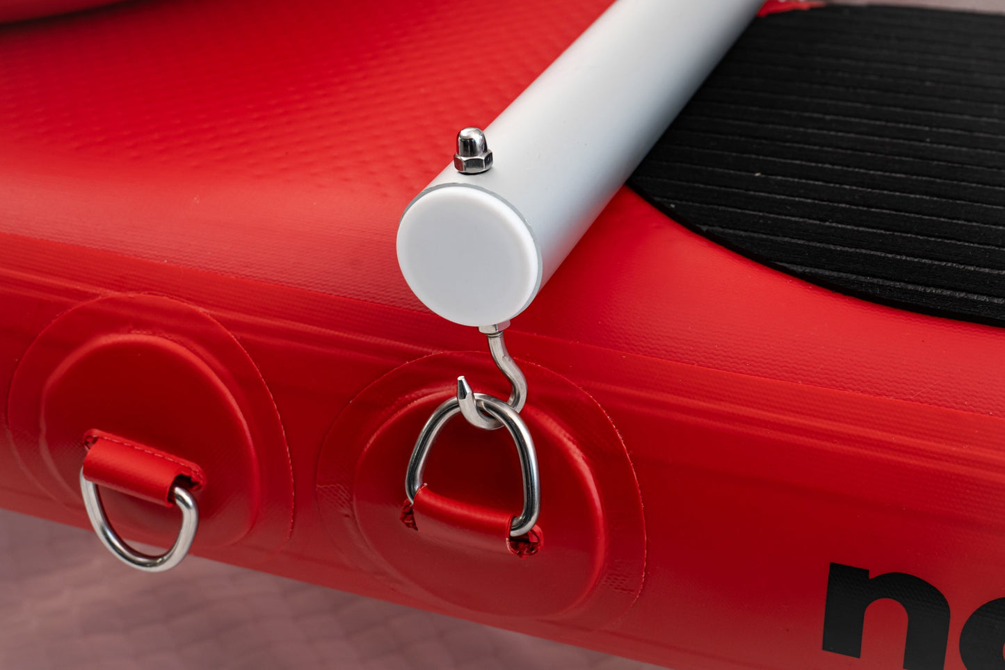 Close-up of a red scooter with a white handle and black seat, featuring a hook and 'n' logo.