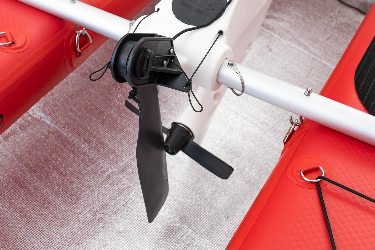 Close-up of a red and white drone with a propeller on a textured surface